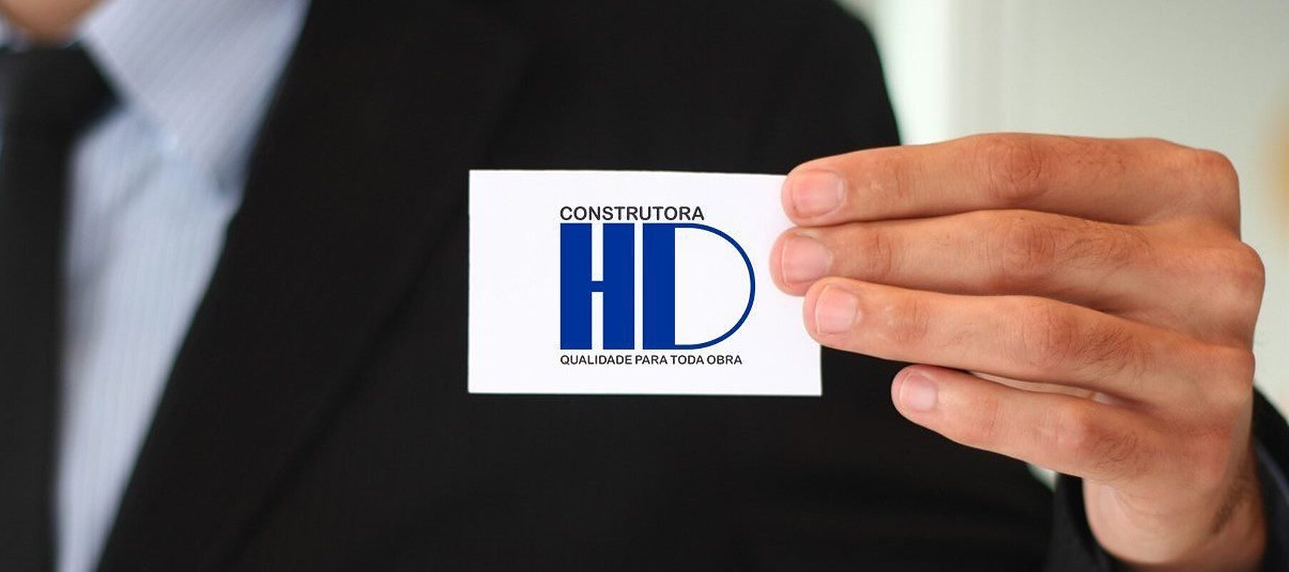 Profissional da Construtora HD segurando o cartão de visitas da empresa